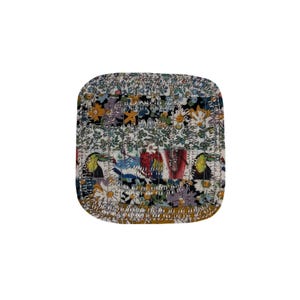 May include: Square, quilted coaster with a floral and toucan pattern. The coaster features a mix of colours including white, blue, yellow, and red. The edges are rounded and the bottom edge is a solid gold colour.
