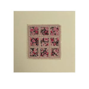 May include: A pink and black floral fabric square with a frayed edge, framed on a cream card.