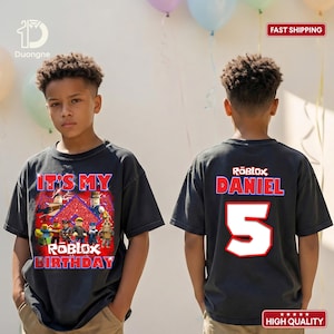 May include: Black t-shirt with a Roblox birthday design. The front features the text "IT'S MY ROBOLX BIRTHDAY" with cartoon characters. The back displays "ROBLOX DANIEL 5" in red and white.