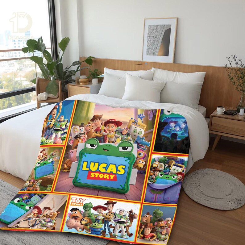 Op de afbeelding: Een pluche deken met een kleurrijke collage van Toy Story-personages en een centraal groen, kikker-vormig kader met de tekst Lucas Story in gele en rode letters, uitgestald over een wit bedsprei in een slaapkameromgeving.