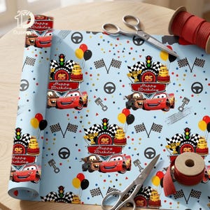Op de afbeelding: Lichtblauw cadeaupapier met een herhaald patroon van raceauto's, verjaardagstaarten, ballonnen en geblokte vlaggen. De tekst "Happy Birthday" en "95" zijn zichtbaar. Rood lint en schaar zijn ook aanwezig.