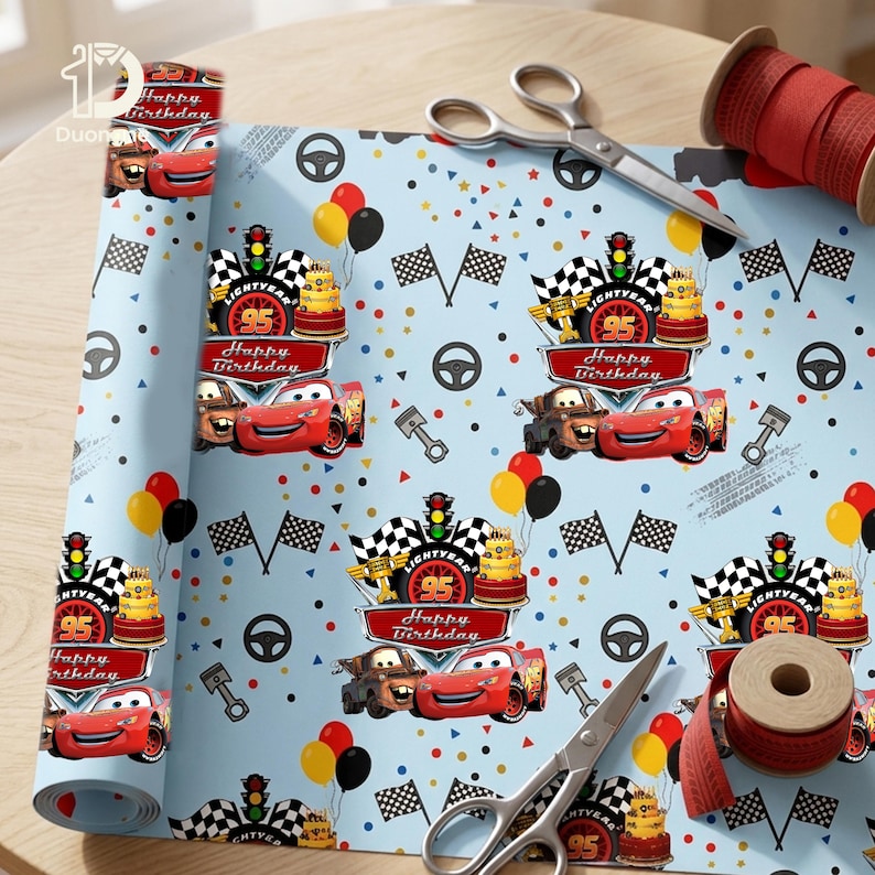 Op de afbeelding: Lichtblauw cadeaupapier met een herhaald patroon van raceauto's, verjaardagstaarten, ballonnen en geblokte vlaggen. De tekst "Happy Birthday" en "95" zijn zichtbaar. Rood lint en schaar zijn ook aanwezig.