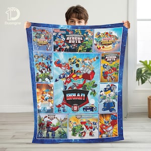 Pode incluir: Um cobertor azul com tema Transformers, apresentando imagens de desenhos animados de robôs e o nome "BRIAN". O cobertor tem uma borda estrelada e vários painéis com diferentes designs de robôs.