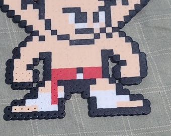 Puede incluir: Un personaje de pixel art hecho de cuentas marrones, blancas, negras y rojas. El personaje es un hombre de dibujos animados con una coleta marrón, que lleva un cinturón rojo y zapatos blancos.
