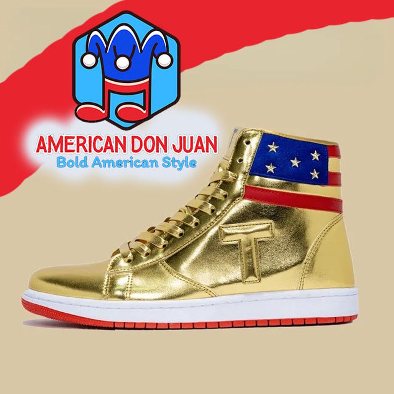Puede incluir: Zapatillas doradas de ca&ntilde;a alta con un dise&ntilde;o de bandera americana roja, blanca y azul en la parte posterior. Las zapatillas tienen una suela blanca con una franja roja alrededor del borde. El texto "AMERICAN DON JUAN Bold American Style" es visible en la imagen.