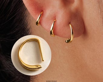 May include: Three gold hoop earrings of varying sizes are worn in the earlobe. A circular inset shows a single gold hoop earring with a smooth, curved design and a small, engraved star detail at the tapered end. The text water & star jewelry is visible.