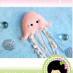 May include: A pink felt jellyfish with white lace tentacles and pearl accents. The jellyfish is on a blue background with glitter. The text "JELLYFISH" is at the top of the image. The text "Wal Artesanal" and "Copyright 2020 - Wal Treira" is at the bottom of the image. The text "...Nothing is small if it's done for love..." is also at the bottom of the image.