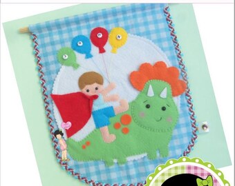 May include: A felt banner with a blue and white checkered background. A boy in a red cape is riding a green dinosaur with orange spikes. The dinosaur has a happy face and there are five balloons with letters on them. The banner has a brown and blue trim. The text on the banner reads "Boy and the Dinosaur" and "O Menino e O Dino".