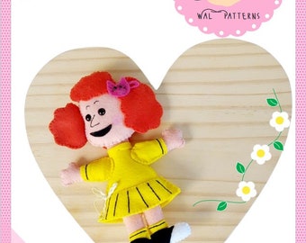 May include: A felt doll named Frieda, with red hair, a yellow dress, and black shoes, is displayed on a wooden heart-shaped plaque. The plaque has a floral design with white flowers and green leaves. The text "2024 by Wal Vieira" and "NOTHING IS SMALL IF IT'S DONE FOR LOVE" are also on the plaque.
