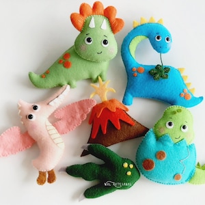 May include: A set of five felt dinosaur toys, including a green dinosaur, a blue dinosaur, a pink dinosaur, a green dinosaur in an egg, and a red volcano. The toys are handmade and feature embroidered details.