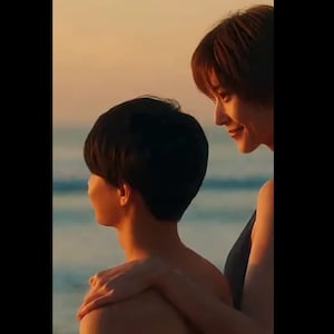 以下が含まれることがあります： 夕焼けのビーチにいる2人。一人はもう一方の肩に腕を回している。空はオレンジと黄色の混ざり合いで、背景には海が見える。