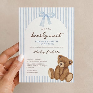May include: A rectangular baby shower invitation card featuring a light blue and white vertical striped border, a central arch, a watercolor blue bow at the top, and a brown teddy bear illustration with the text We can bearly wait for Baby Smith.