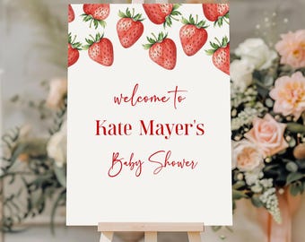 Könnte beinhalten: Ein weißes Willkommens-Schild mit roten Erdbeeren am Rand. Der Text lautet "Willkommen zur Babyparty von Kate Mayer".
