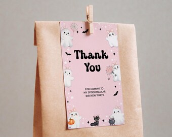 Może przedstawiać: Różowa etykieta prezentowa z czarnym napisem "Thank You", otoczona kreskówkowymi duchami, nietoperzami i gwiazdami. Etykieta jest przymocowana do brązowej papierowej torby za pomocą drewnianego klipsa. Na etykiecie znajduje się również tekst "FOR COMING TO MY SPOOKTACULAR BIRTHDAY PARTY".