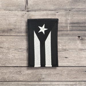 Peut inclure: Écusson brodé noir et blanc représentant le drapeau de Porto Rico. Le patch rectangulaire a un fond noir avec une étoile blanche et trois rayures blanches.