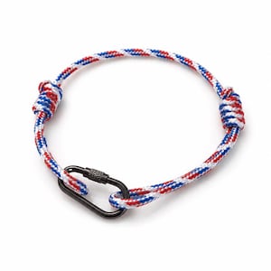 Peut inclure: Un bracelet en corde tressée rouge, blanc et bleu avec un fermoir mousqueton noir. Le bracelet est noué aux deux extrémités. La circonférence de la corde est d'environ 18 cm.