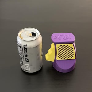 May include: An open silver soda can next to a purple and yellow can opener. The can opener has a yellow lever and a diagonal striped design. The can has the text "Refresh Then Recycle".