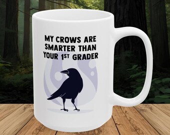 May include: White ceramic mug with a black crow illustration and the text "MY CROWS ARE SMARTER THAN YOUR 1ST GRADER". The crow is set against a light purple and white background.
