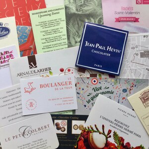 May include: A collection of various rectangular business cards and promotional flyers from Parisian establishments, including Jean-Paul H&eacute;vin, Le Boulanger de la Tour, and Pierre Herm&eacute;, featuring diverse typography, logos, and graphic illustrations.