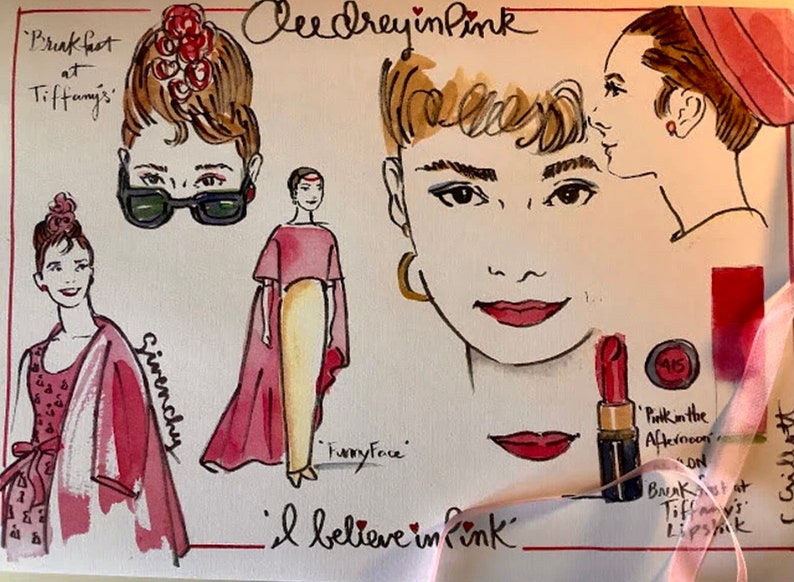 May include: A watercolor illustration of Audrey Hepburn in various poses, including a close-up of her face with red lipstick. The text "Audrey in Pink" and "I believe in pink" are written on the page. The illustration is a whimsical and colorful depiction of the iconic actress.