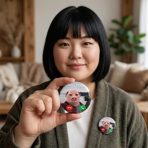 Könnte beinhalten: Eine Person hält zwei runde Buttons. Jeder Button zeigt ein Schweinegesicht mit dem Text "John Pork is calling". Die Buttons haben rote und grüne Telefonanrufsymbole. Der Hintergrund zeigt eine Landschaft.