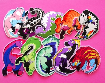 May include: A collection of colorful dinosaur stickers on a pink background. The stickers feature various dinosaur designs with different color schemes, including rainbow, pink, blue, green, and purple. The stickers are likely made of vinyl or a similar material.
