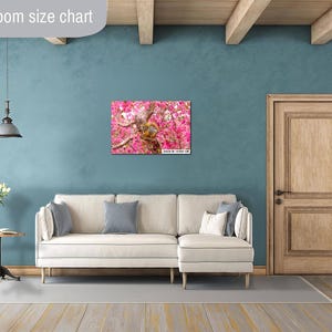 Puede incluir: Un sof&aacute; blanco con un lienzo de estampado floral colgado en la pared encima. El sof&aacute; est&aacute; en una habitaci&oacute;n con una puerta de madera y un techo de madera.