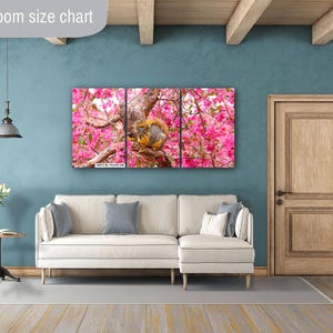 Puede incluir: Una impresi&oacute;n de arte de pared de tres paneles con una ardilla posada en una rama de un &aacute;rbol de flores rosas. La ardilla es marr&oacute;n y blanca con una cola tupida. El &aacute;rbol est&aacute; en plena floraci&oacute;n con flores rosas.