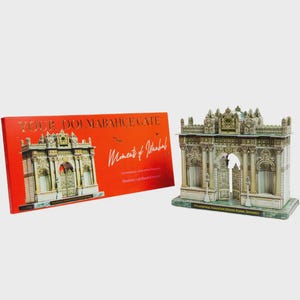 May include: A detailed cardboard model of the Dolmabahçe Gate from Istanbul, alongside its red box. The model showcases architectural details and text. The box reads "Your Dolmabahçe Gate" and "Moments of Istanbul".