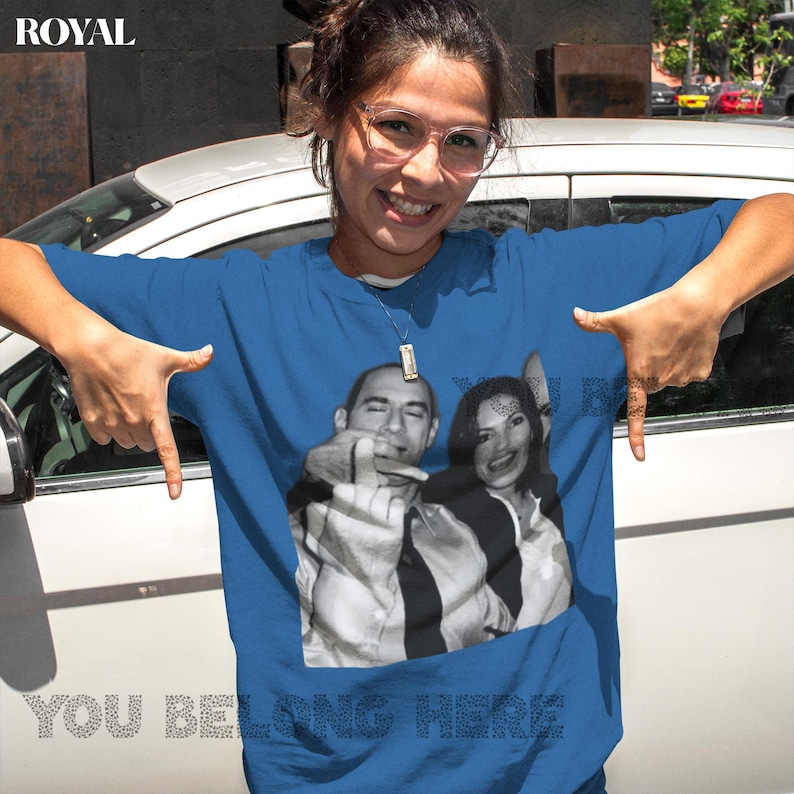 May include: A royal blue t-shirt with a graphic print of three people. The text "You Belong Here" is printed on the bottom of the shirt.