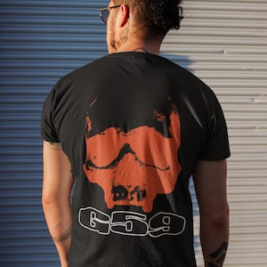 May include: A black t-shirt featuring a large orange skull graphic and the text "G59" printed in white on the back.
