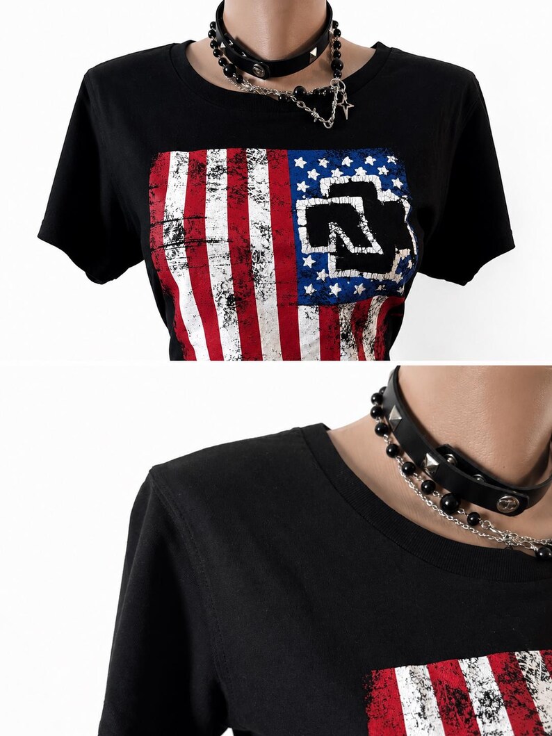 Puede incluir: Una camiseta negra de manga corta con un gr&aacute;fico de bandera estadounidense desgastada y el logotipo de Rammstein en negro superpuesto. La prenda se combina con una gargantilla de cuero negro decorada con tachuelas plateadas, cuentas y cadena.