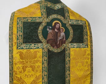 May include: A religious vestment with a yellow and green floral pattern. The green section features an image of a religious figure holding a child. The vestment has a cross design with ornate gold trim.