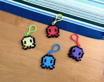 Puede incluir: Cuatro llaveros de pulpo pixelados de colores brillantes con ojos negros y un esquema de colores verde, amarillo, azul y rojo. Cada llavero tiene un anillo de plástico para sujetarlo a una bolsa o llaves.