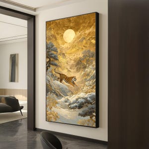 Puede incluir: Una impresión artística enmarcada representa un tigre saltando sobre un paisaje montañoso nevado bajo una luna llena. La obra de arte presenta una paleta de colores dorados y blancos con pinceladas detalladas, creando una escena dramática y majestuosa.