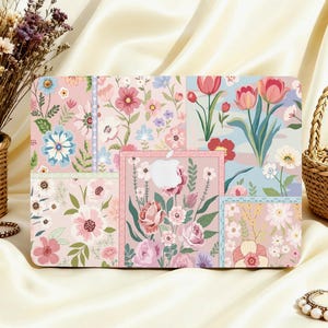 Può includere: Una custodia rigida rettangolare per computer portatile con un design a collage floreale a più pannelli. Il motivo include vari fiori rosa, rossi, blu e bianchi su sfondi pastello, con un ritaglio centrale per il logo Apple sulla superficie.