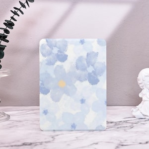 Puede incluir: Un fondo blanco con un patrón floral de acuarela azul. Las flores son de color azul claro con un centro amarillo.