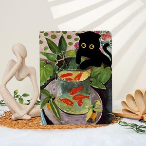 May include: A decorative art print featuring a black cat with yellow eyes peering over a fishbowl with orange fish. The artwork has a colorful, painterly style with green foliage and a pink background.