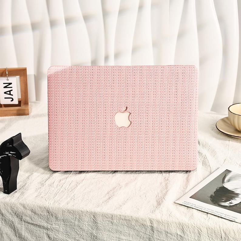 May include: Pink laptop case with a woven texture and the Apple logo in the center.