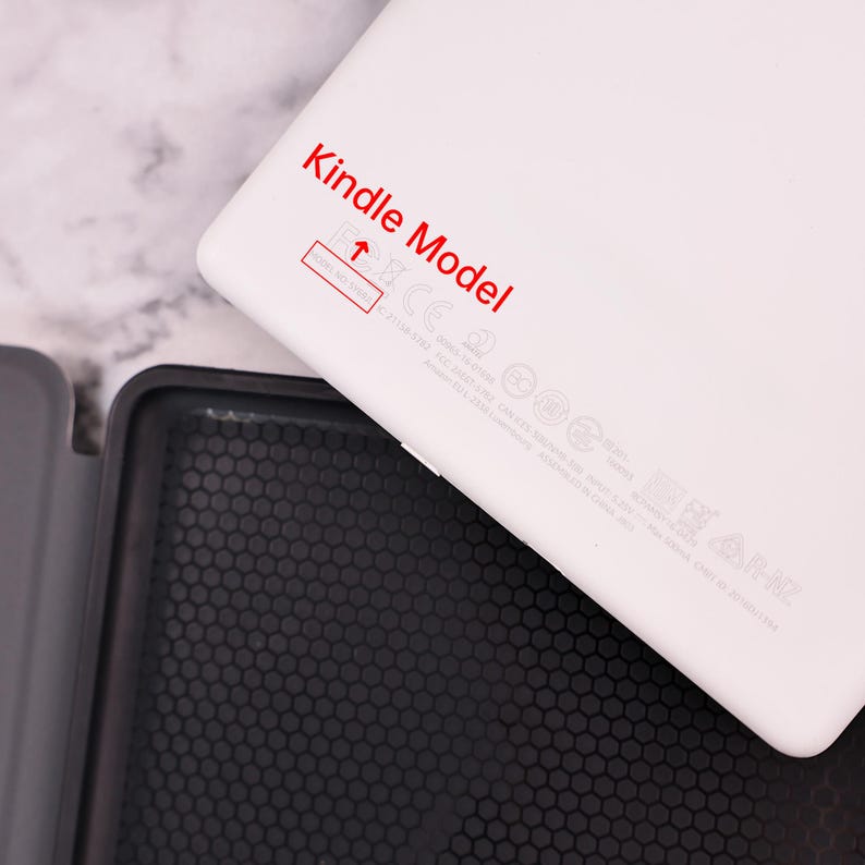 May include: White Kindle e-reader with the text "Kindle Model" printed in red on the back. The back also includes various regulatory markings and logos.
