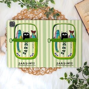 May include: A light green striped tablet case featuring two sardine cans with a black cat and colorful fish. The cans are labeled "Sardines" and "In Olive". The case has a whimsical, cartoon-like design.