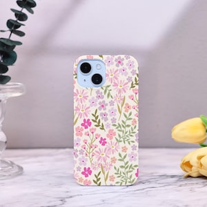 Puede incluir: Funda de tel&eacute;fono con dise&ntilde;o floral. El dise&ntilde;o presenta flores rosas, moradas y melocot&oacute;n con hojas verdes sobre un fondo crema. La funda del tel&eacute;fono tiene un m&oacute;dulo de c&aacute;mara azul claro.