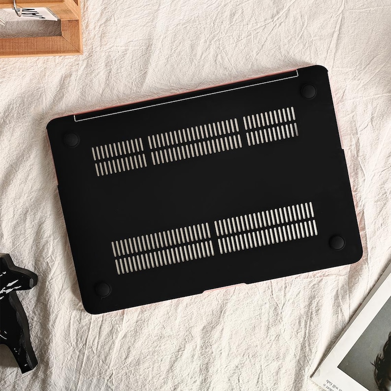 May include: Black laptop case with a textured surface and a pink trim. The case has a series of small holes for ventilation.