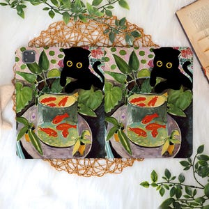 May include: A tablet case featuring a whimsical design. The case showcases a black cat silhouette with yellow eyes, perched above a goldfish bowl. The background includes a floral and foliage pattern with a pink and green color scheme.