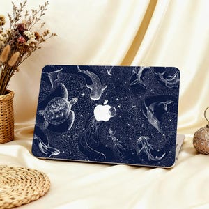 May include: A navy blue laptop case featuring a white illustration of various marine animals, including a sea turtle, whale shark, and jellyfish. The design is set against a starry background, with the Apple logo visible.