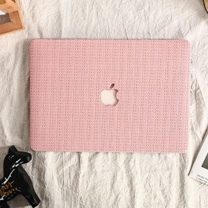 May include: A pink laptop case with a woven texture and a cut-out apple logo.