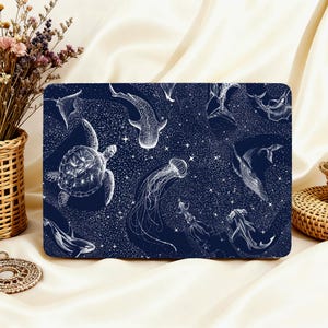 May include: A rectangular navy blue laptop sleeve featuring a white illustration of various marine animals, including a sea turtle, jellyfish, and whale shark. The design includes a starry background.