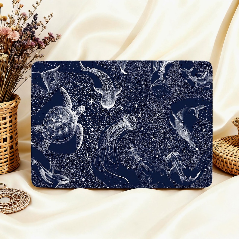 May include: A rectangular navy blue laptop sleeve featuring a white illustration of various marine animals, including a sea turtle, jellyfish, and whale shark. The design includes a starry background.