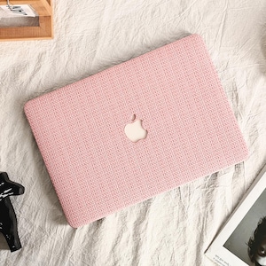 May include: A pink laptop case with a woven texture and a white Apple logo.