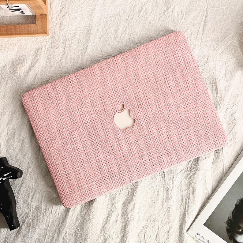 May include: A pink laptop case with a woven texture and a white Apple logo.